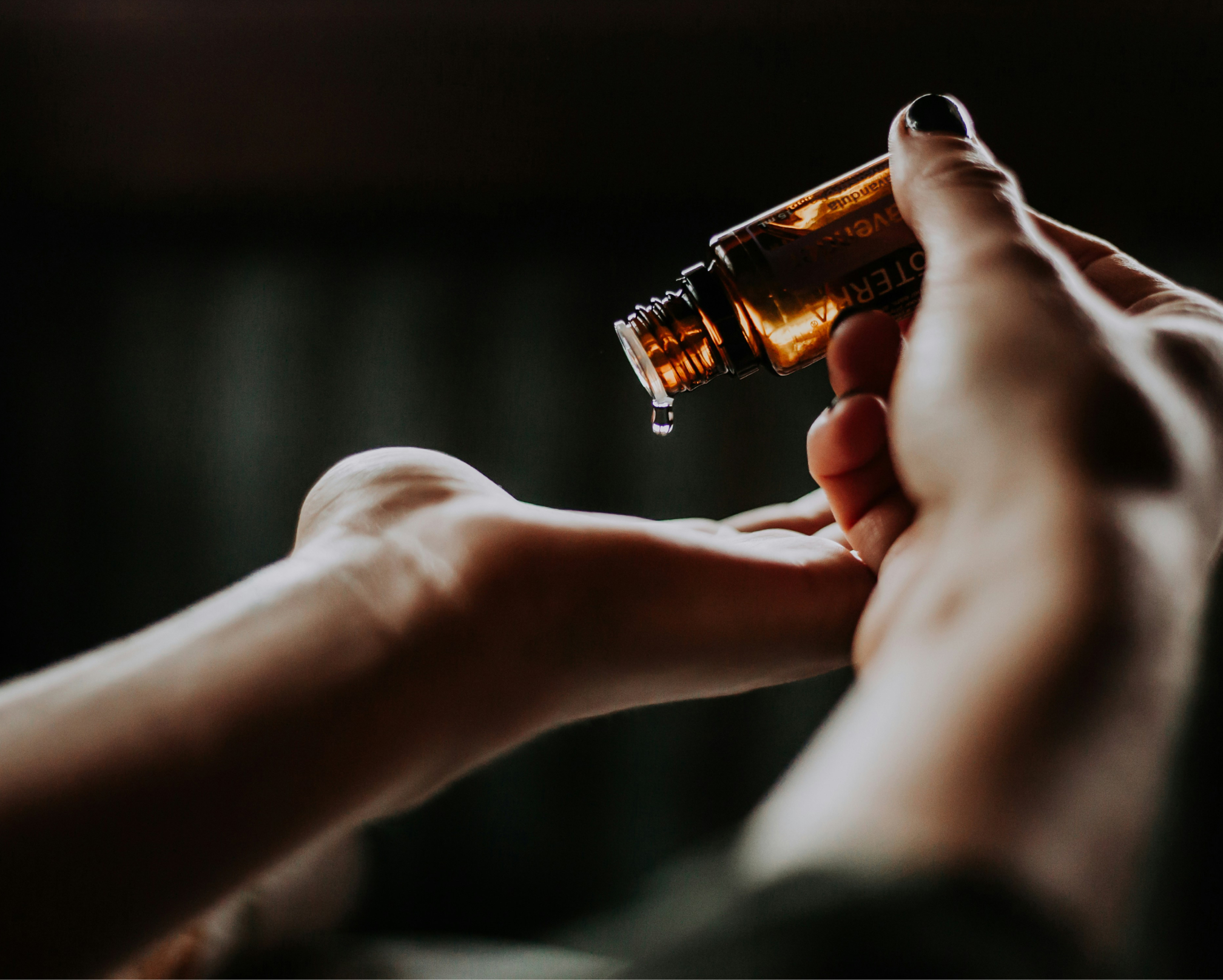 Massageolja hälls ut i hand i ett mörkt rum